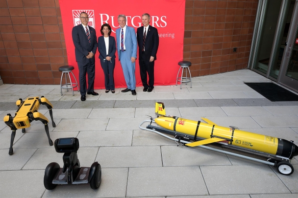 Rutgers and elected officials pose in front of robots at the Engineering School.